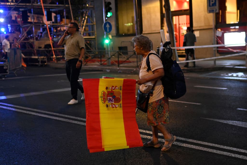 Una mujer vende banderas españolas frente a la sede del Partido Popular en Madrid, este domingo 23 de julio de 2023.