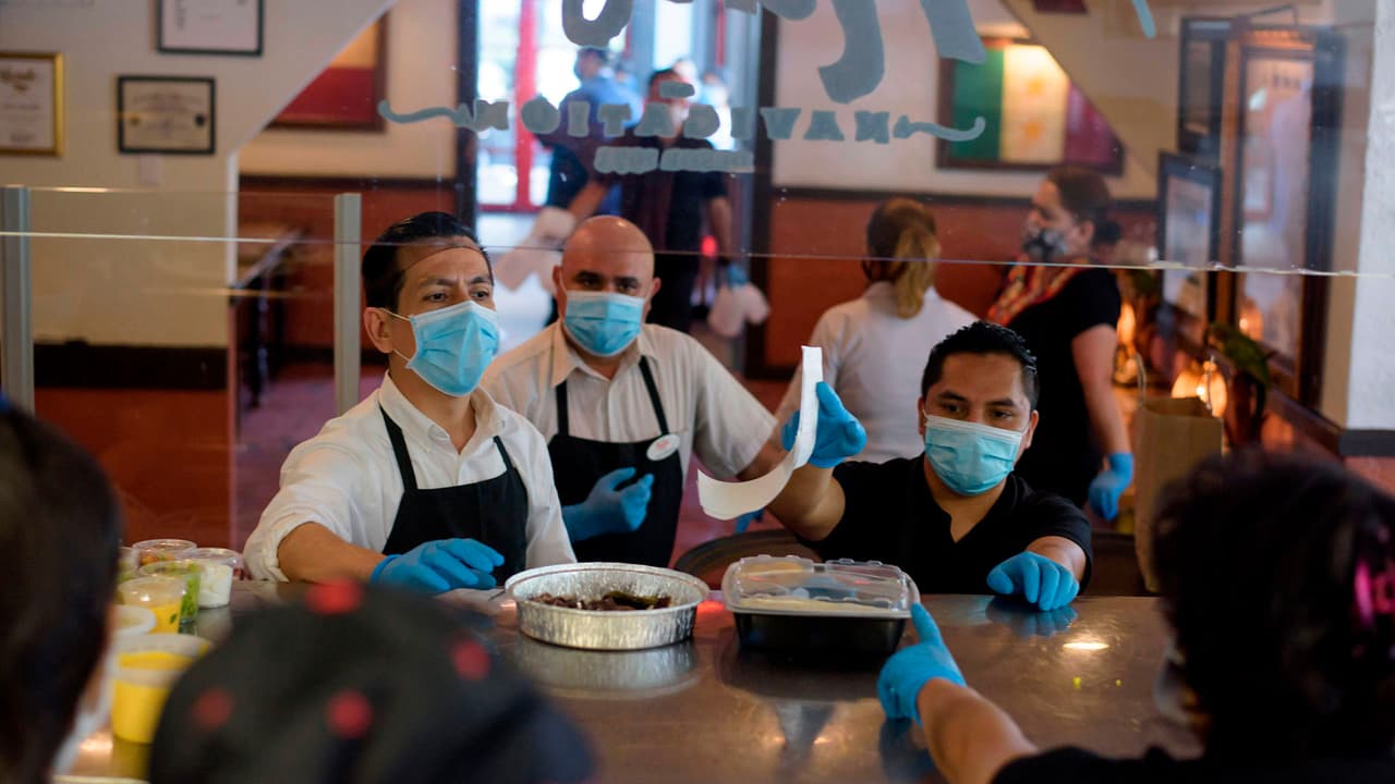 Trabajadores de The Original Ninfa's usan guantes y mascarillas mientras toman pedidos para llevar a la cocina