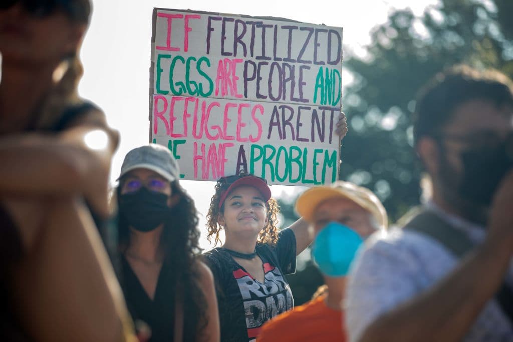 "Si los óvulos fertilizados son personas y los refugiados no, entonces tenemos un problema", dice el cartel de una chica en la manifestación llevada a cabo en Austin.