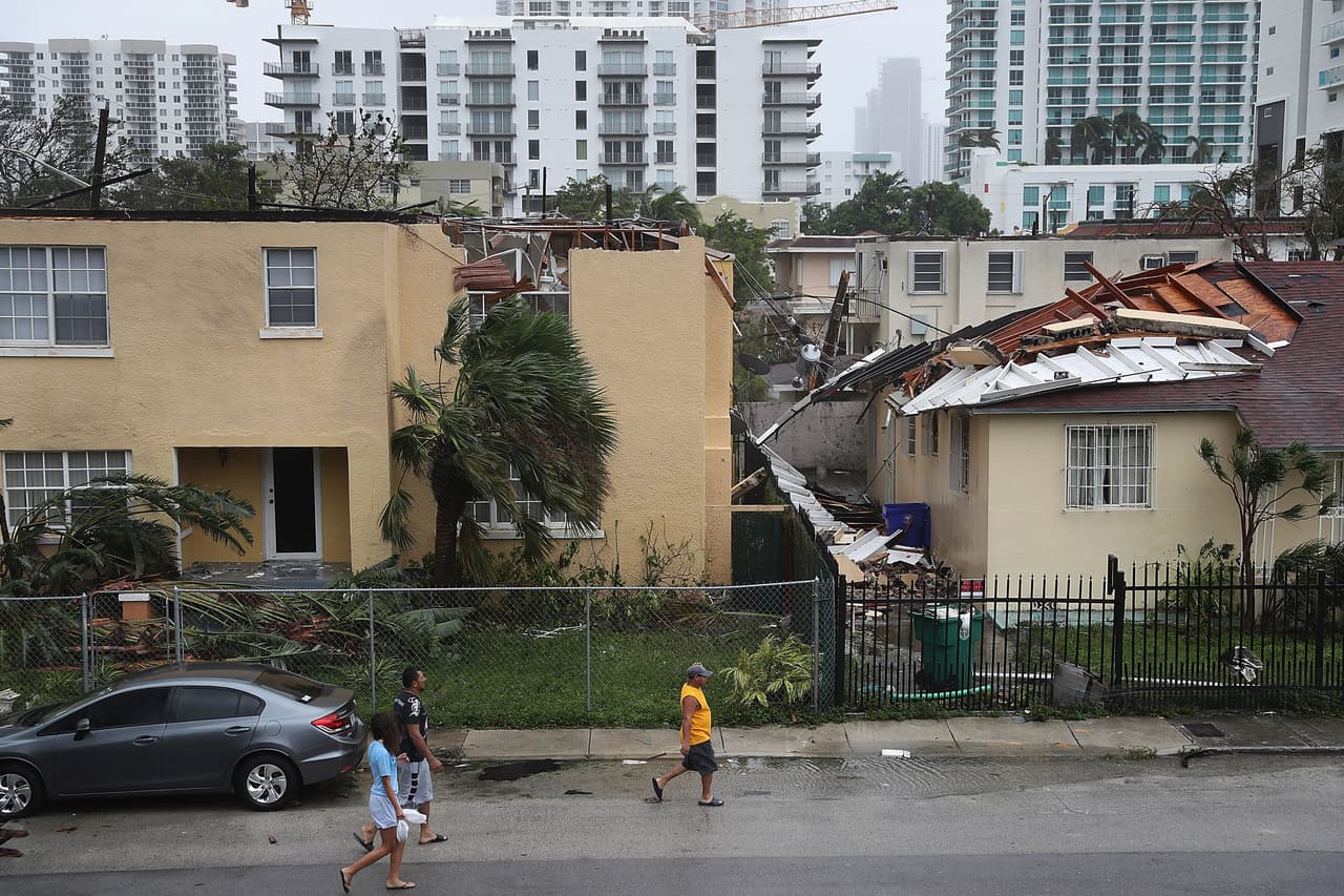 En la imagen, varias persoans caminana a pesar del toque de queda que las autoridades decretaron por el paso de Irma. Detrás de ellos se ve un techo que fue arrancado por la fuerza de los vientos en Brickell.