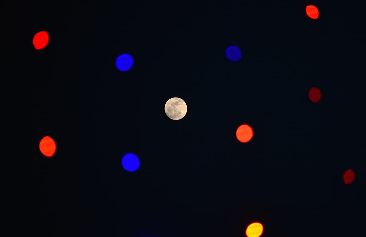 <b>India. </b>Una superluna se observa en el cielo junto a luces decorativas en Jalandhar.