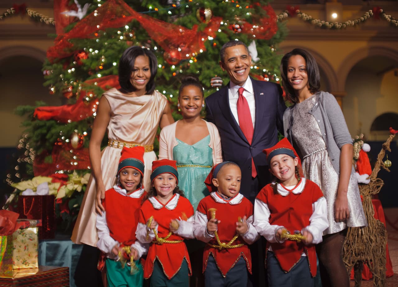 El palo de rosa y los cuellos drapeados han sido elecciones de moda muy comunes en el armario de Michelle Obama. Así también lo hizo para la navidad del 2012 llevando su vestido creado por Byron Lars, de seda y cinturón dorado. Sus dos hijas hicieron de los cárdigans los protagonistas.