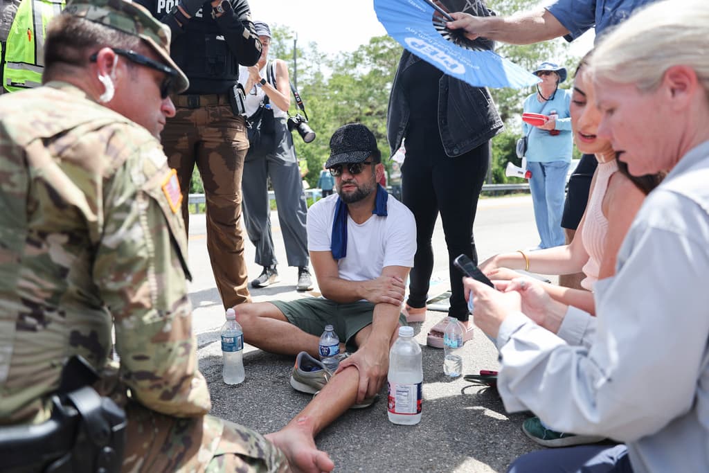 <b>El camarógrafo Alberto Boal, de la agencia EFE</b>, permanece sentado en el suelo tras sufrir un atropello en el pie a las afueras del Centro de Entrenamiento y Transición Dade-Collier, conocido como Alcatraz de los Caimanes. El incidente ocurrió mientras cubría las protestas y la visita de legisladores al centro, una instalación que actualmente alberga a más de 900 migrantes bajo condiciones que han sido calificadas de inhumanas por defensores de derechos humanos y organizaciones civiles.