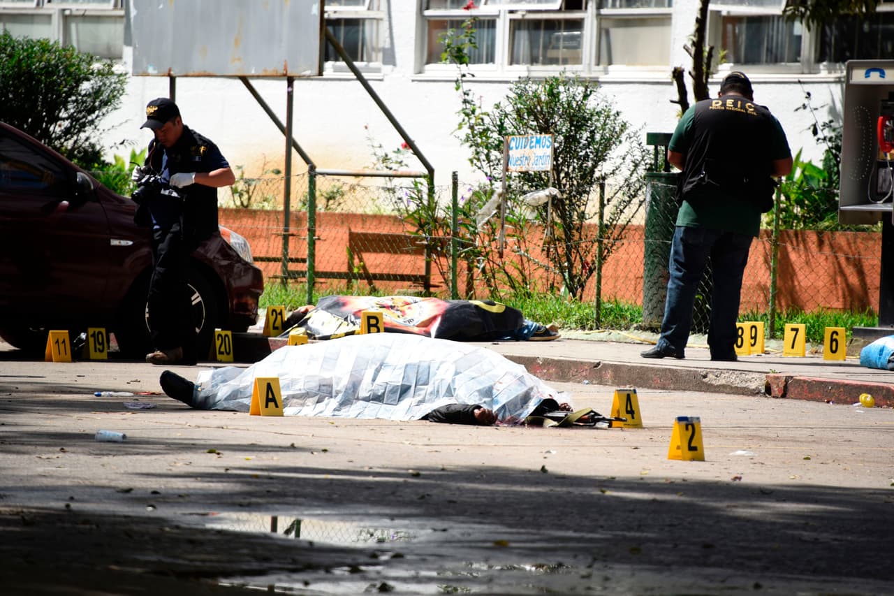 Forensic personnel work on the place where the bodies of a prison guard (front) and of a civilian caught in the crossfire were shot dead by presumed gang members and lie covered, outside the Roosevelt Hospital, in Guatemala City on August 16, 2017. At least four people were killed and several others wounded when presumed gang members shot dead two prison guards and seriously wounded a third in Guatemala City, raising the toll of policemen killed so far this year to 24, authorities said. Two civilians, including an eight-year-old child, were also killed in the crossfire and several more wounded. / AFP PHOTO / JOHAN ORDONEZ (Photo credit should read JOHAN ORDONEZ/AFP/Getty Images)