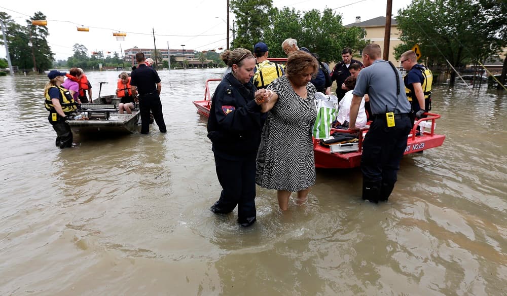 Rescatistas ayudan a residentes a abandonar sus casas debido a las inundaciones en la ciudad.