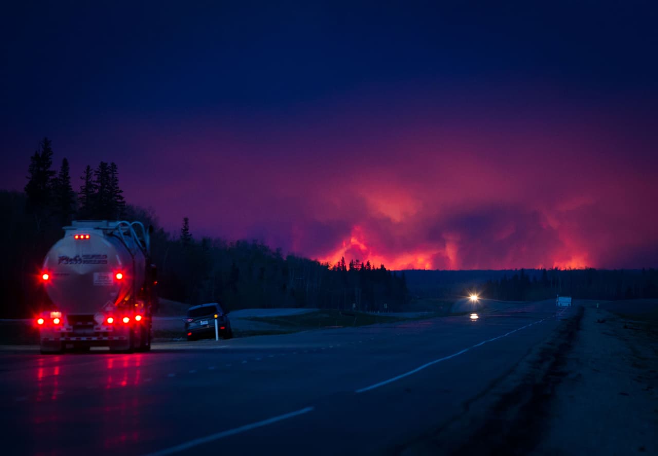 A lo lejos el fuego ilumina el horizonte nocturno de Fort McMurray.