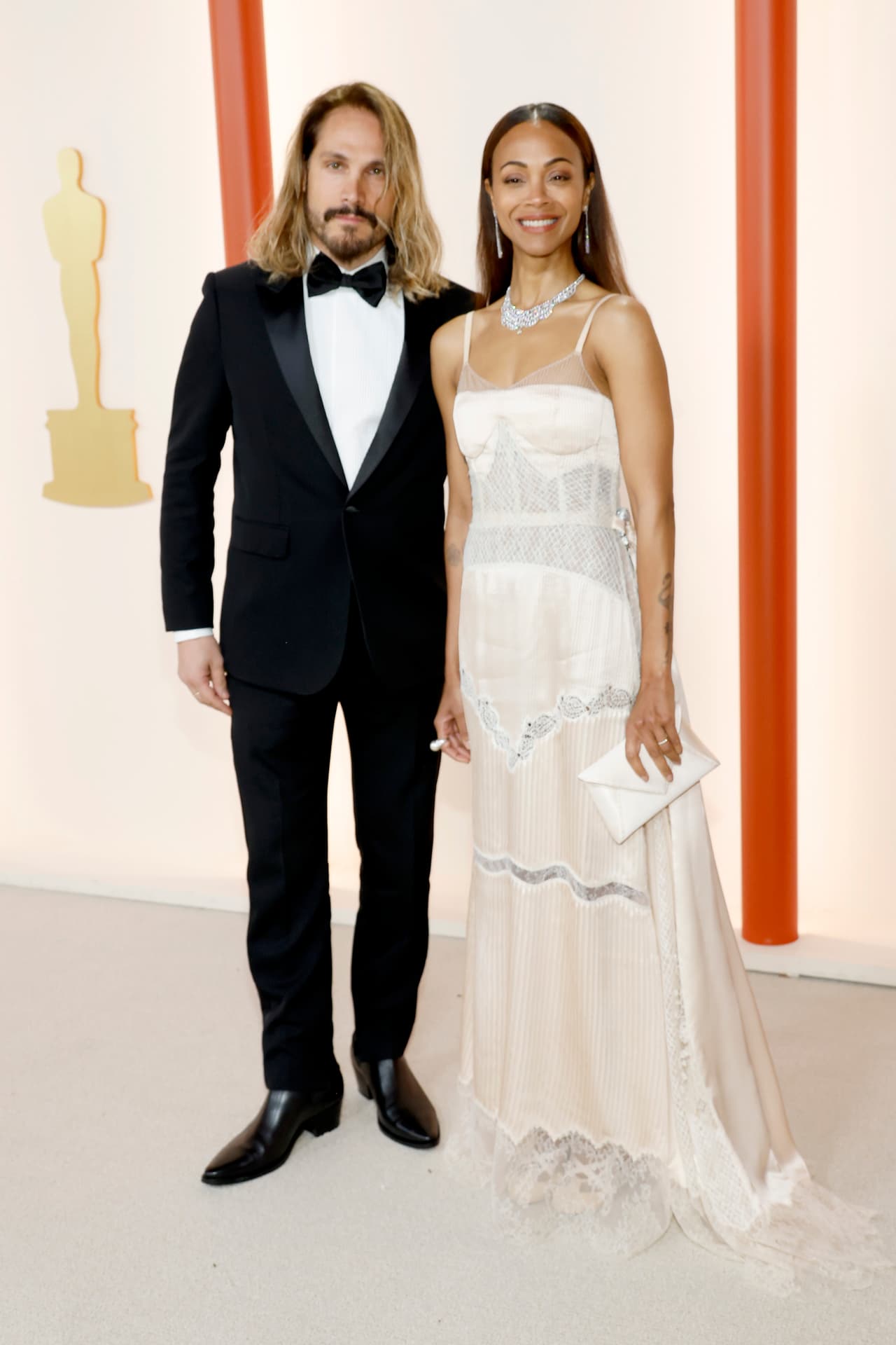 Marco Perego y Zoe Saldana en la alfombra champagne de los Premios Oscar 2023