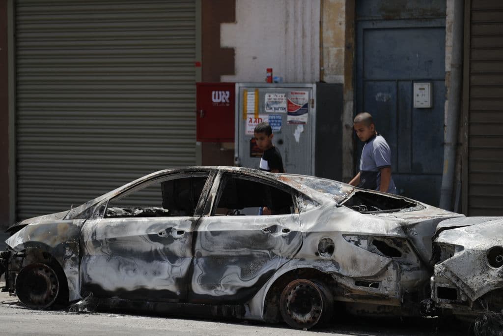 En la ciudad de Lod, cerca de Tel Aviv,
<b> se pueden apreciar imágenes como la de dos jóvenes que observan un auto estacionado completamente calcinado</b> a causa de la violencia que ha escalado entre judíos y palestinos que comparten la urbe.
