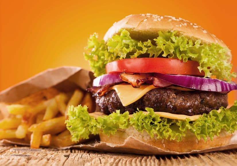 Deliciosa hamburguesa cocinada en leña o carbón con papas fritas y vegetales frescos