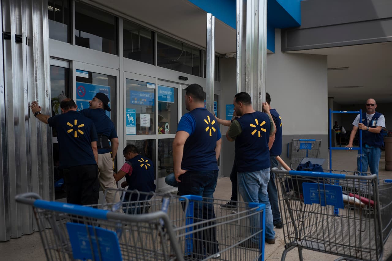 Trabajadores de Walmart en la ciudad de Humacao, al extremo oriental de la isla, protegen las ventanas de la tienda. El secretario de Transporte reconoció que siguen reparando carreteras dañadas o bloqueadas por María.