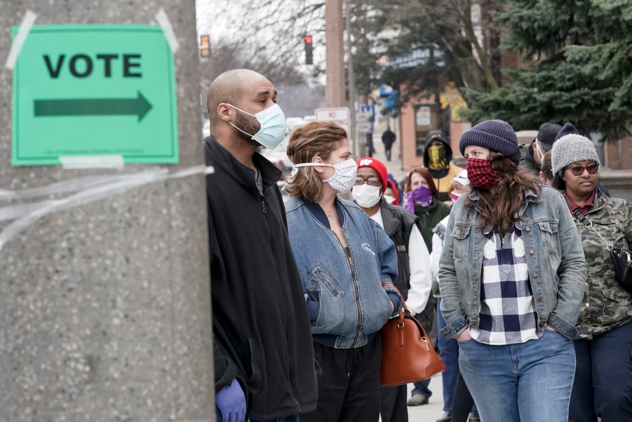 Una fila de votantes protegidos con máscaras contra el coronavirus frente a la secundaria Riverside de Milwaukee, Wisconsin. Los residentes de este estado tuvieron que ignorar la orden de quedarse en casa debido al covid-19 para participar en las elecciones primarias, una realidad que deberán enfrentar otros estados en las próximas semanas.