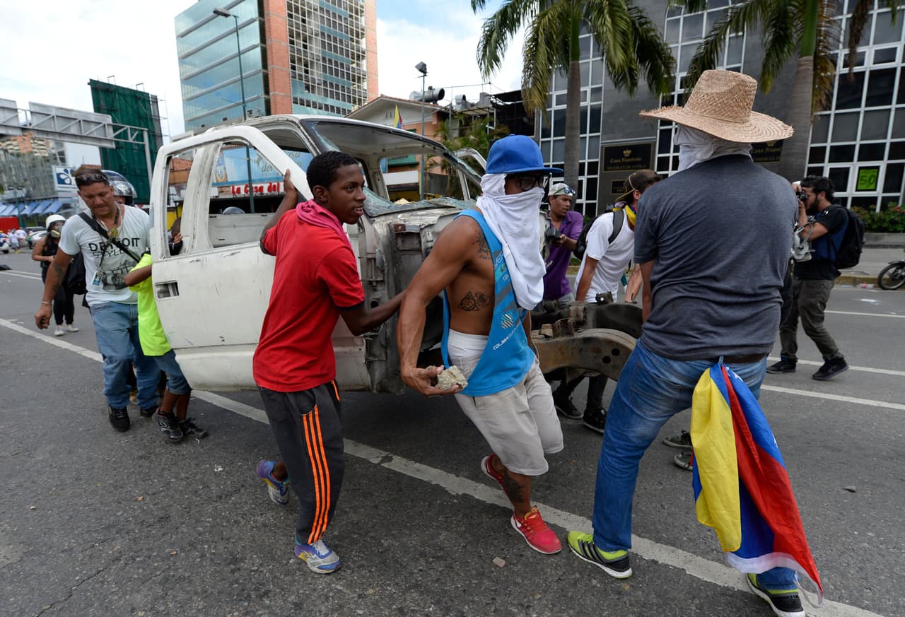 Manifestantes desmantelan un carro viejo para usarlo como barricada, al enfrentarse con la policía antidisturbios en Caracas. Los encuentros violentos comenzaron cuando la policía que impidió el paso hacia el centro de la ciudad. La convocatoria principal había terminado pacíficamente.