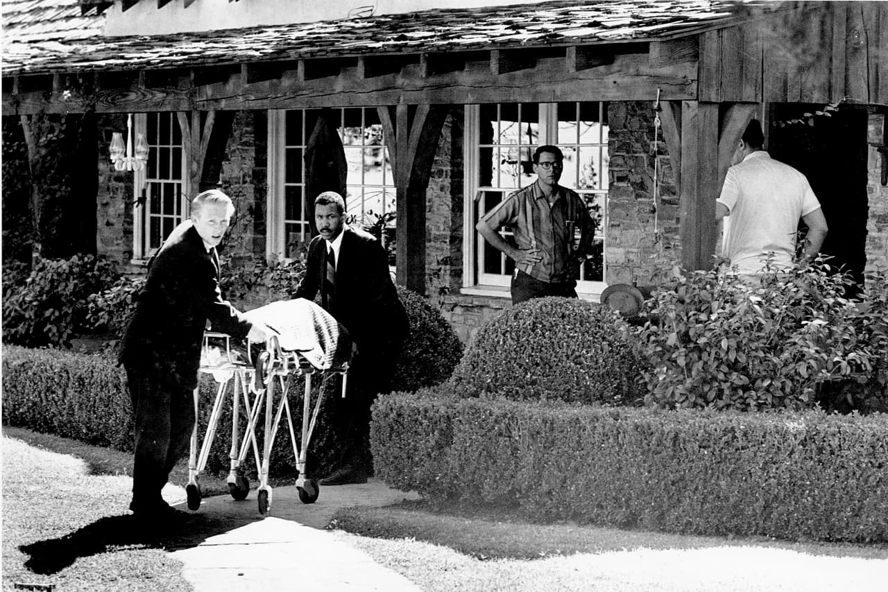 Una noche de agosto dos miembros de la familia Manson entraron a la casa de Leno y Rosemary LaBianca y los mataron a puñaladas. A la noche siguiente otra parte de la secta irrumpió en la casa donde vivían el director de cine Roman Polansky y su esposa, la actriz Sharon Tate, que estaba en el octavo mes de su embarazo. La fotografía es del momento en que las autoridades retiran cadáveres de la mansión de Polanski.