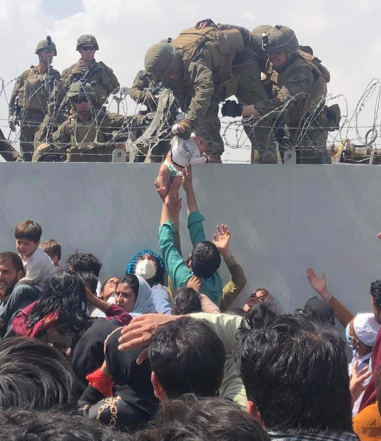Un soldado estadounidense toma un bebé sobre el muro del aeropuerto de Kabul el 20 de agosto, desde donde han sido evacuadas unas 10,400 personas en las últimas 24 horas. Ante las dificultades para ingresar al aeródromo y tomar un avión para escapar del régimen
<a href="https://www.univision.com/temas/taliban"><u>Talibán</u></a>, algunos adultos han entregado niños a los soldados estadounidenses sobre el límite del aeropuerto.