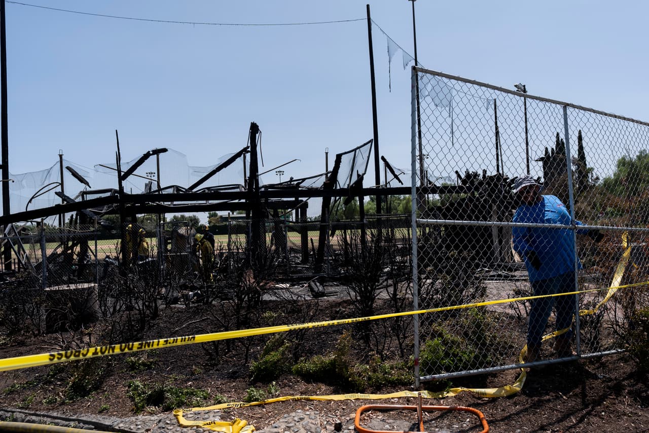 A worker sets up a fence outside Jay Littleton Ball Park, a historic baseball field that appeared in "A League of Their Own" and other movies, in Ontario, Calif., Friday, Aug. 23, 2024, after fire destroyed the grandstands at the ballpark. (AP Photo/Jae C. Hong)