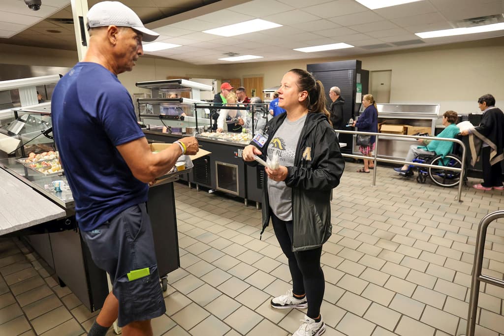 <b>Orden ante todo:</b> La administradora de las escuelas de Pasco, Jill Cortier, habla con Muhamed Aftah durante un servicio de comida en un refugio para huracanes en la escuela secundaria/preparatoria River Ridge en preparación para el huracán Milton, el miércoles 9 de octubre de 2024, en New Port Richey, Florida.