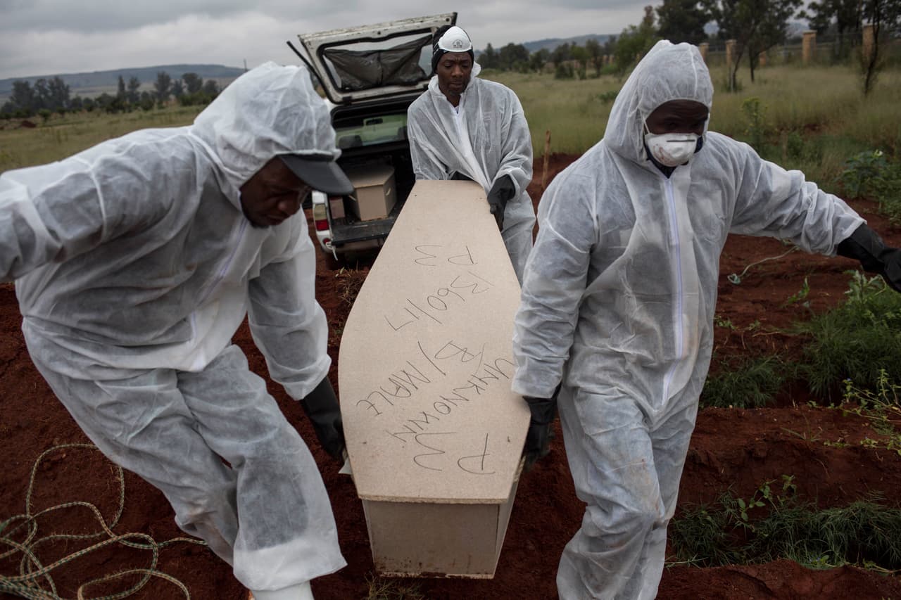 Trabajadores funerarios cargan con el féretro de un hombre no identificado para su entierro en un cementerio a las afueras de Johannesburgo. En cada tumba se colocan al menos cinco cuerpos de personas no identificadas. La imagen fue tomada el 12 de abril de 2018. (AP Foto/Bram Janssen)