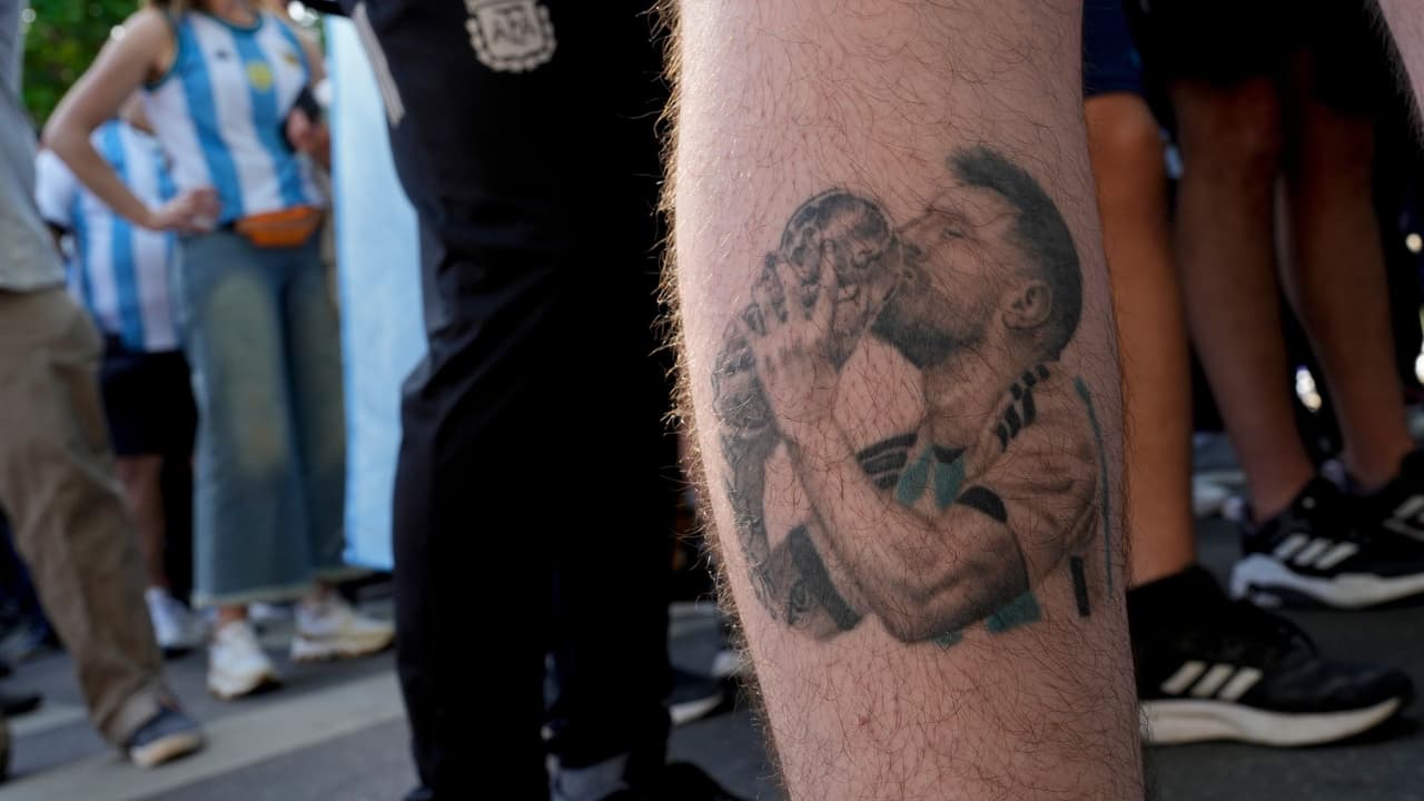 Un hombre con un tatuaje del jugador de fútbol Lionel Messi besando el trofeo de la Copa Mundial camina fuera del estadio La Bombonera antes de un partido de fútbol de clasificación para la Copa Mundial de la FIFA 2026 entre Argentina y Uruguay en Buenos Aires, Argentina, el jueves 16 de noviembre de 2023.