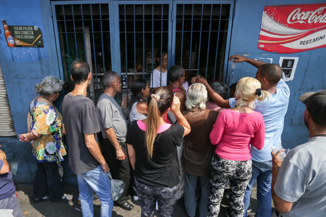 Algunos residentes de la capital intentan comprar alimentos en una tienda a oscuras. En algunas zonas de Caracas la luz regresó cerca del mediodía del viernes, pero de forma intermitente. Otras zonas del interior de Venezuela están sin energía eléctrica desde hace un día.