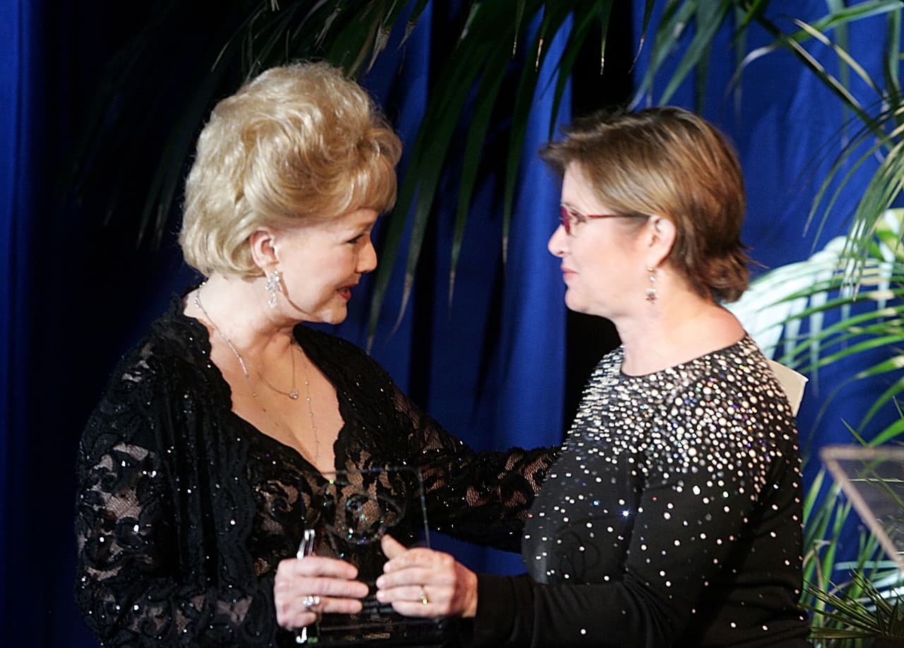 BEVERLY HILLS, CA - FEBRUARY 19: Actress Carrie Fisher presents "Lacoste Presidents Award" to her mother Debbie Reynolds onstage at the 7th Annual Costume Designers Guild Awards at the Beverly Hilton Hotel on February 19, 2005 in Beverly Hills, California. (Photo by Frazer Harrison/Getty Images)