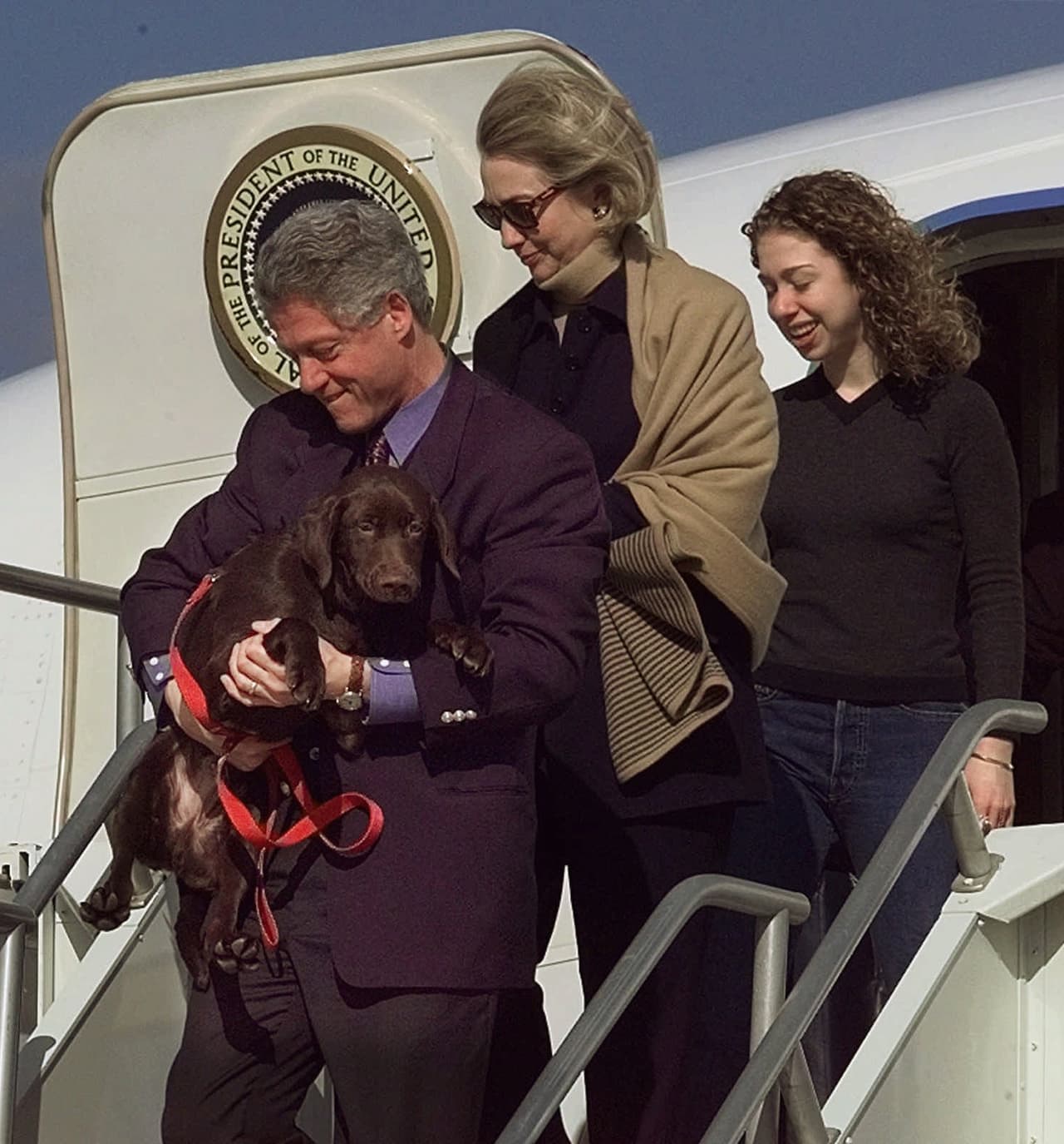 Bill Clinton, su esposa Hillary y su hija Chelsea en la escalinata del Air Force One con su único perro, un
<i>Labrador Retriever</i> llamado '`Buddy'.