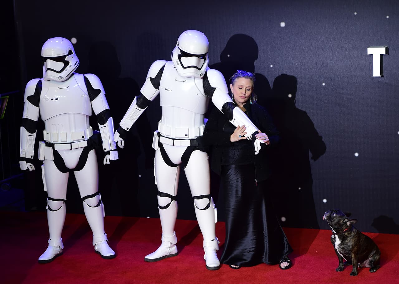Carrie Fisher con un storm trooper y su perro, Gary, en la premiere europea de 'Star Wars: The Force Awakens' en el centro de Londres, el 16 de diciembre de 2015. LEON NEAL/AFP/Getty Images.