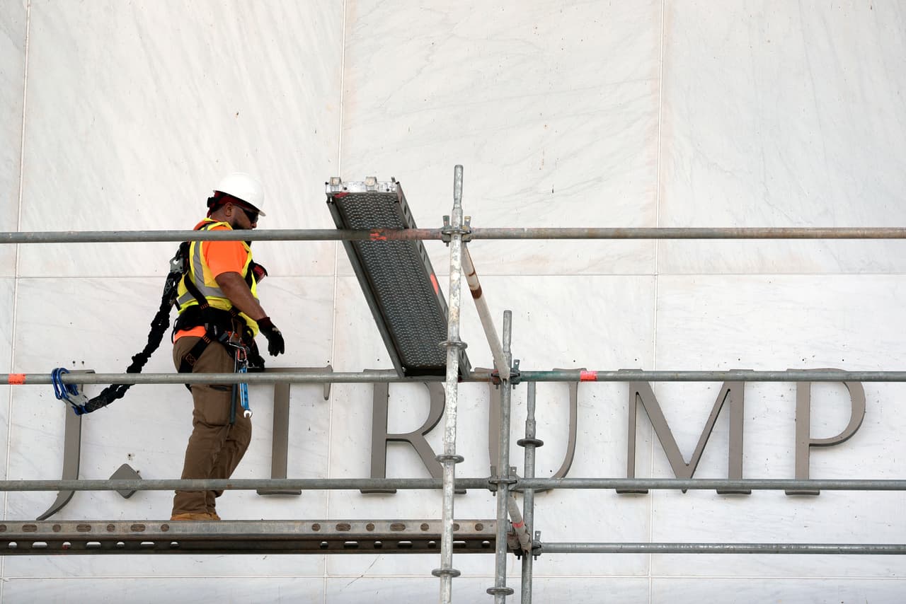 Un trabajador instala andamios frente al letrero del Centro John F. Kennedy para comenzar con la remoción del nombre "Trump".
