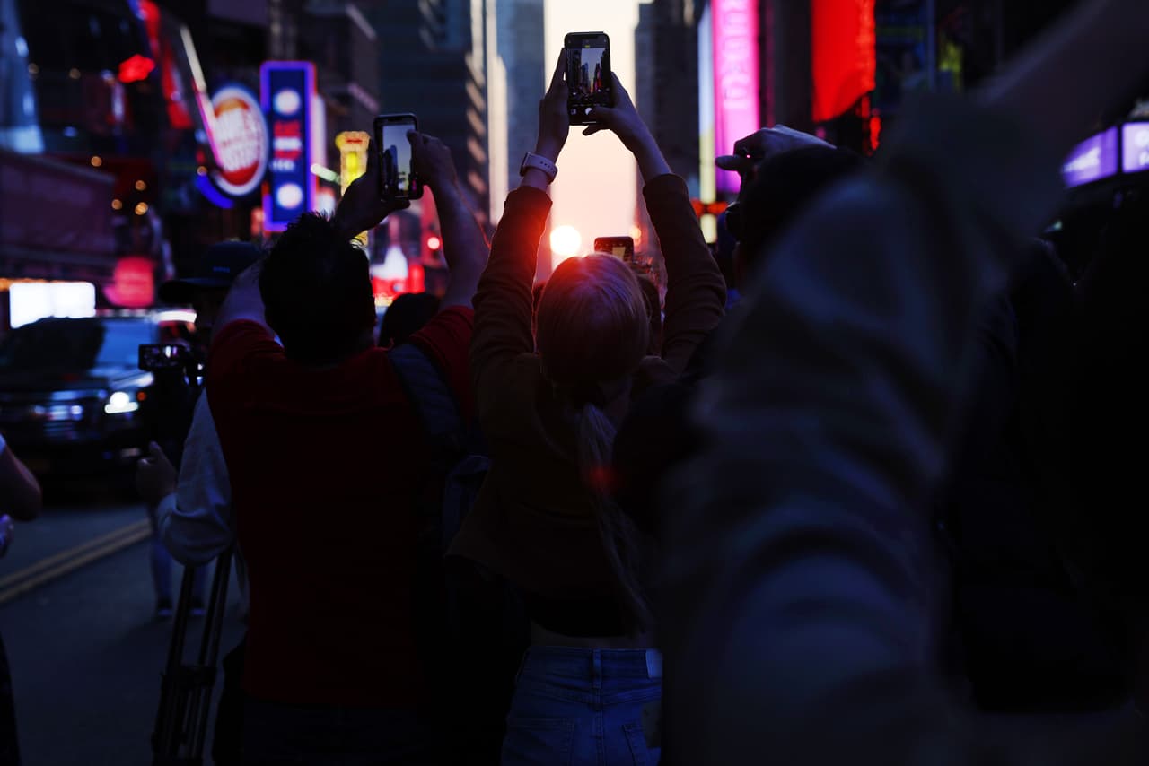 La gente mira la puesta de sol en la calle 42 en Times Square en una de las cuatro noches del año denominadas "Manhattanhenge" cuando el sol se alinea perfectamente a través de los espacios entre los edificios de la calle de la ciudad de Nueva York
