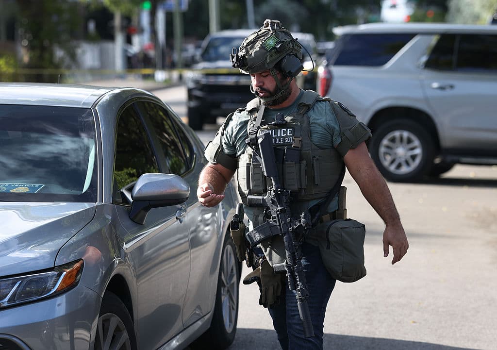 Un agente de policía caminando armado en medio de las calles de Allapattah.