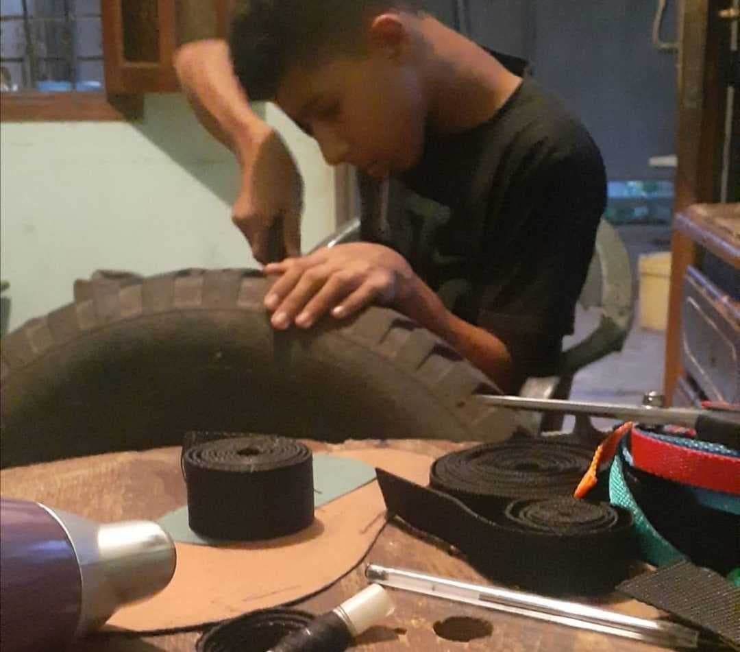 Andrés pasa las tardes en el taller de su abuelo desarmando neumáticos usados para obtener el caucho que le permite producir sus chanclas.