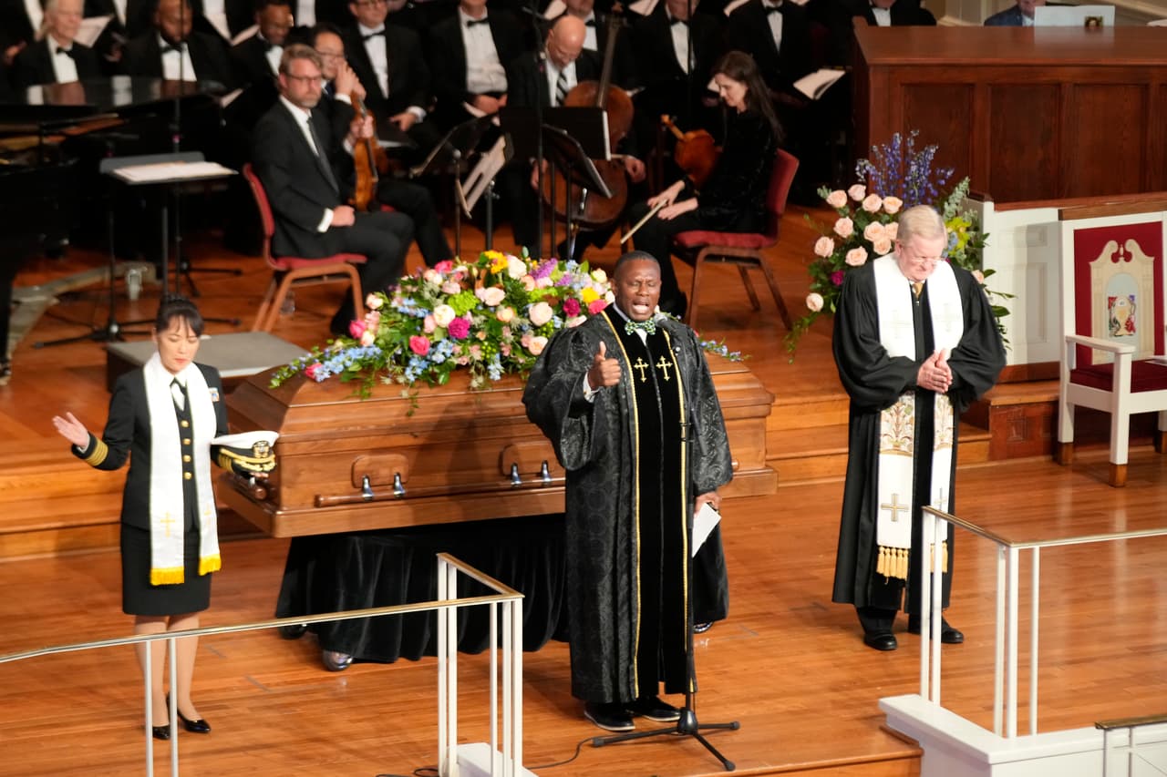 El pastor Tony Lowden, en el centro, ora durante un servicio de homenaje a la ex primera dama Rosalynn Carter.