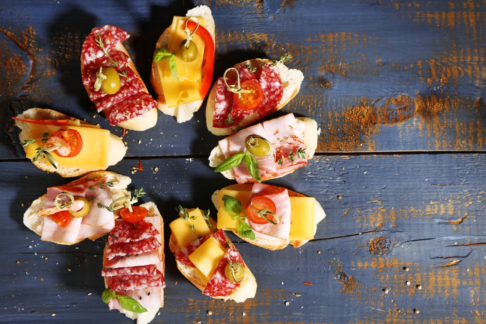 Tapas españolas Las tapas son una receta fácil, ligera y riquísima. Como bocadillos es una excelente opción, solamente tienes que llevar los ingredientes que le quieras poner en pequeños recipientes. Lleva todo ya cortado previamente como pueden ser quesos, jamón, jamón serrano, aceitunas, jitomate. Puedes agregar un poco de aceite de oliva y algunas especias.