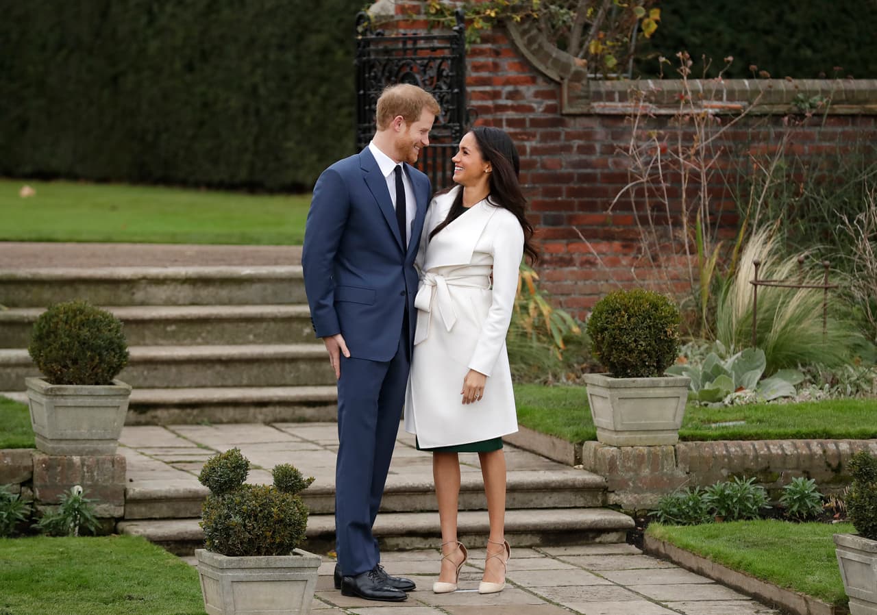 El príncipe Harry luce un traje oscuro como el que usó para las 
<b><a href="https://www.univision.com/noticias/mundo/el-principe-harry-se-compromete-con-una-actriz-divorciada-y-birracial-estadounidense">fotos oficiales del compromiso</a></b> anunciado en noviembre del 2017, aunque Markle lleva un vestido distinto.