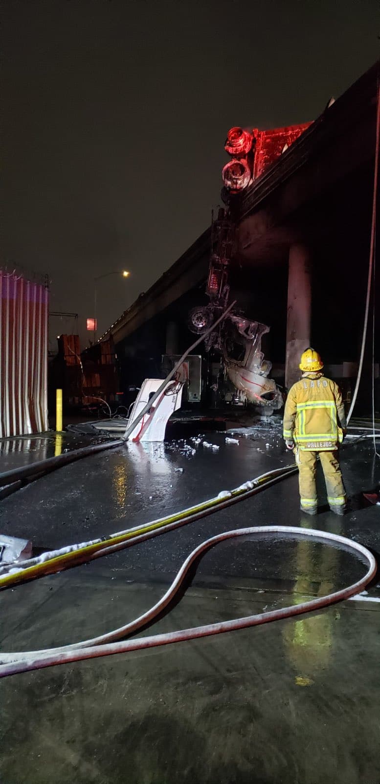 Un camión de carga perdió el control cuando transitaba por un puente, se incendió y parte del vehículo cayó por un costado hacia la calle debajo de la autopista. El chofer logró salir de la cabina de conducción.