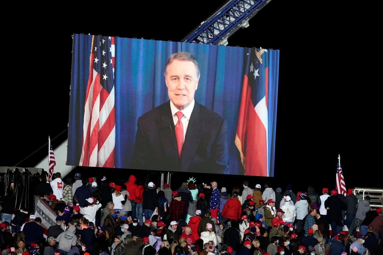 El senador David Perdue envió un mensaje en video que fue transmitido antes de que el presidente Donald Trump llegara a un mitin de campaña en apoyo de los candidatos al senado en Dalton, Georgia, el lunes 4 de enero de 2021. Perdue ha estado ausente en los últimos días después de declararse en cuarentena luego de que un miembro de su equipo fue diagnosticado con covid-19.
