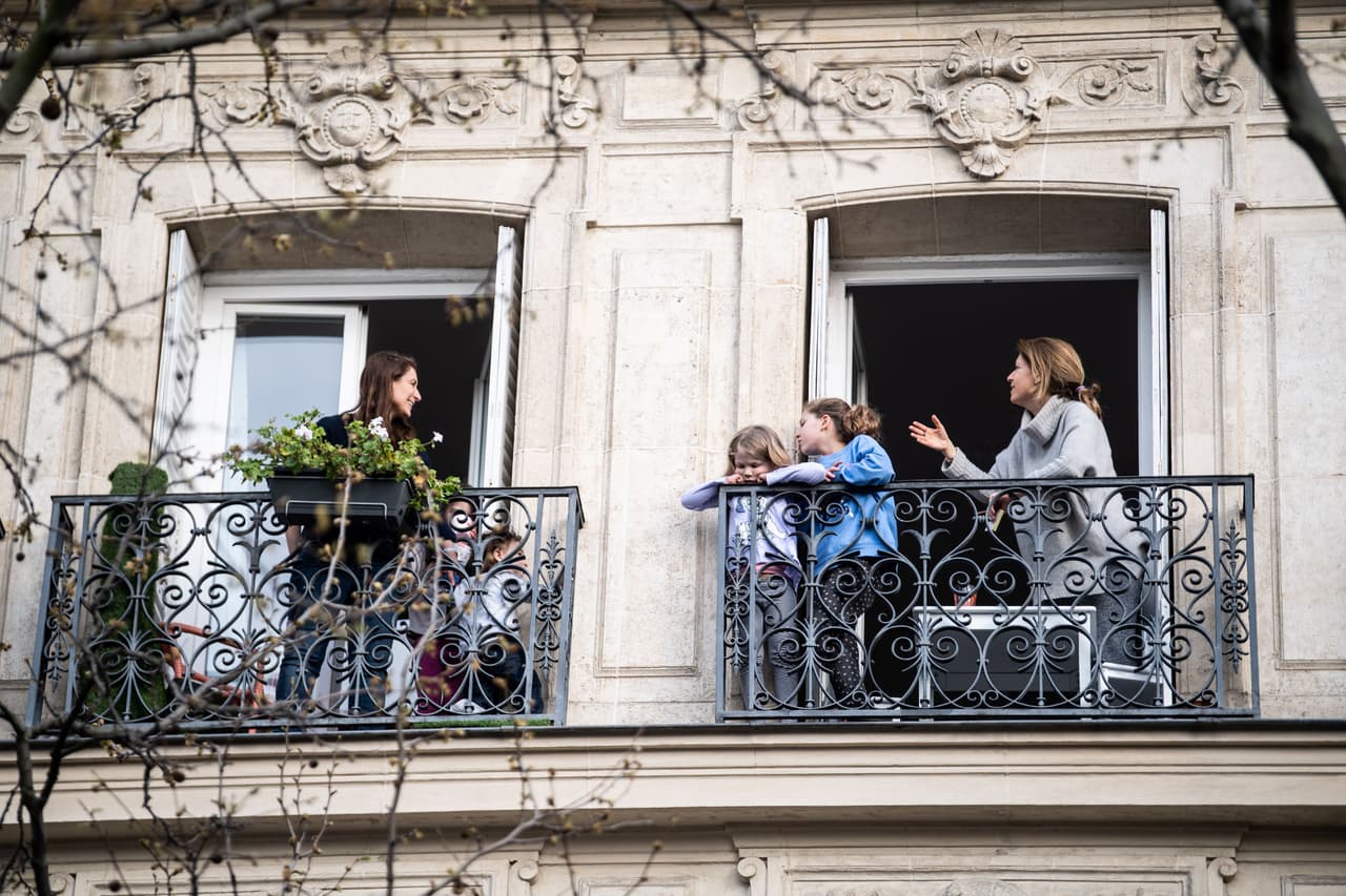 Enfrentando el aburrimiento del encierro, muchas ciudades han visto poblarse sus balcones de vecinos. En esta foto, personas conversan desde sus balcones en París. 
<br>
