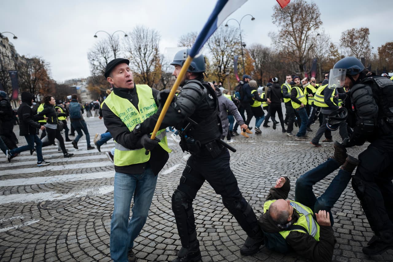 Los manifestantes, quienes visten chalecos amarillos, chocan con agentes de la policía antidisturbios en la avenida Champs-Elysees este sábado. El ministerio de Interior dio cuenta de 19 heridos, cuatro de ellos entre las fuerzas de seguridad, frente a los 106 de la semana anterior, añadió la misma fuente. Hubo 130 personas detenidas, 42 de ellas en París. AP/Kamil Zihnioglu.