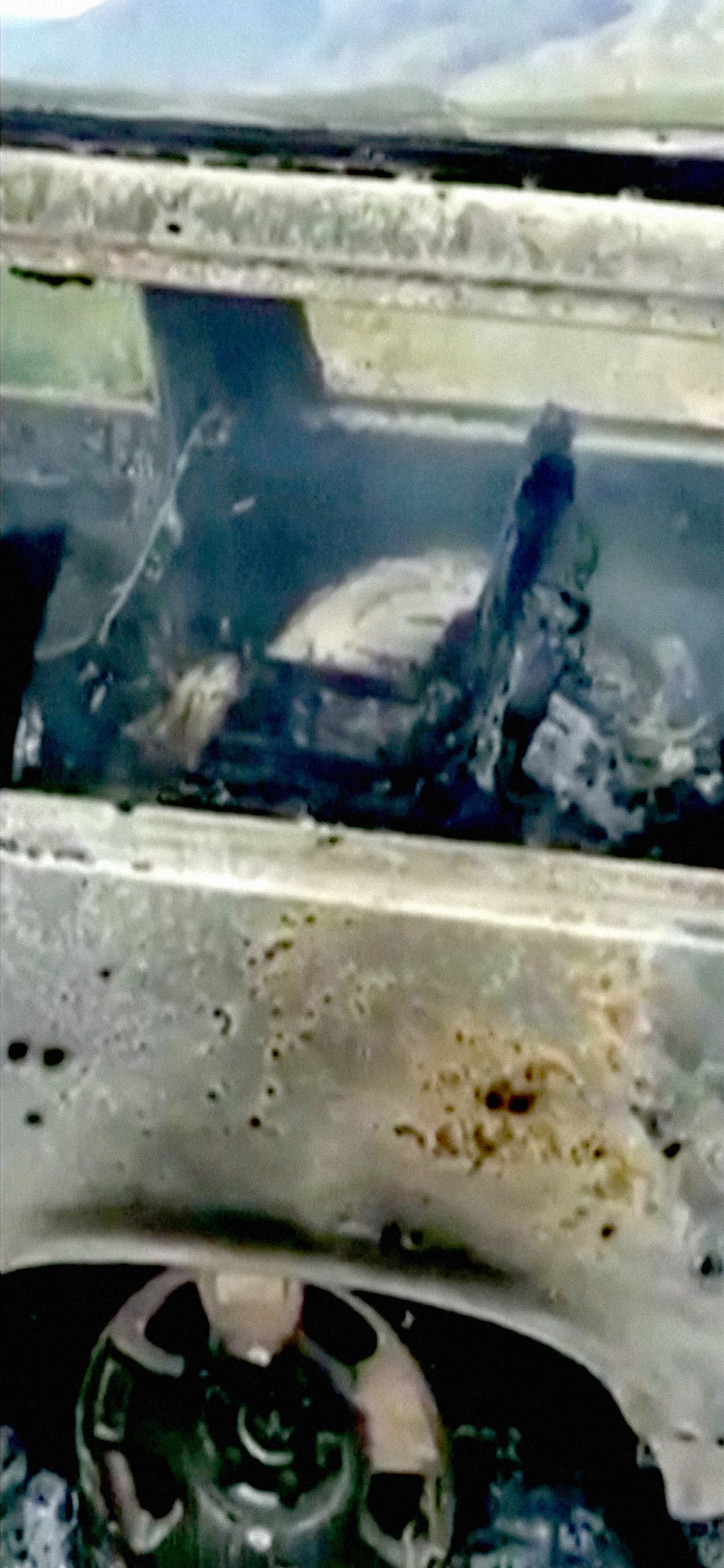 Una captura del video publicado en redes sociales por los familiares, que muestra los restos carbonizados y humeantes de un vehículo plagado de agujeros de bala, en donde aparentemente se transportaban las víctimas cuando ocurrió el ataque.