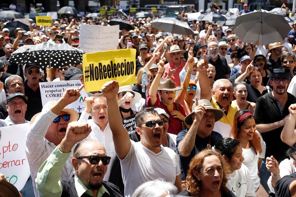 La mujer acusó al presidente de mentir al afirmar que "desde un 1 de diciembre todo va a cambiar", en referencia a la fecha en que López Obrador asumió la presidencia el año pasado. "No todos te creemos, no todos le creemos", añadió. Asimismo, criticó la cancelación de las obras para construir en el municipio de Texcoco un nuevo aeropuerto para la Ciudad de México y el recorte de los fondos para las guarderías infantiles y los refugios para mujeres víctimas de violencia intrafamiliar. En la imagen, un hombre con una pancarta en contra de la reelección de López Obrador, posibilidad que la Constitución actual aún no contempla en México.