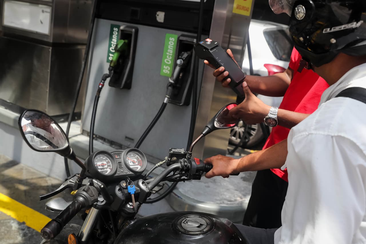 CAR09. CARACAS (VENEZUELA), 21/09/2018.- Un trabajador de PDVSA (Petróleos de Venezuela) explica a un conductor el nuevo método de pago de la gasolina hoy, viernes 21 de septiembre de 2018, en Caracas (Venezuela). La estatal Petróleos de Venezuela (PDVSA) comenzó hoy a instalar en algunas gasolineras de Caracas el nuevo sistema de cobro de los combustibles, antes de que el lunes comience el "período de prueba" decretado por el Gobierno que planea aumentar los precios y limitar los subsidios. EFE/Miguel Gutiérrez