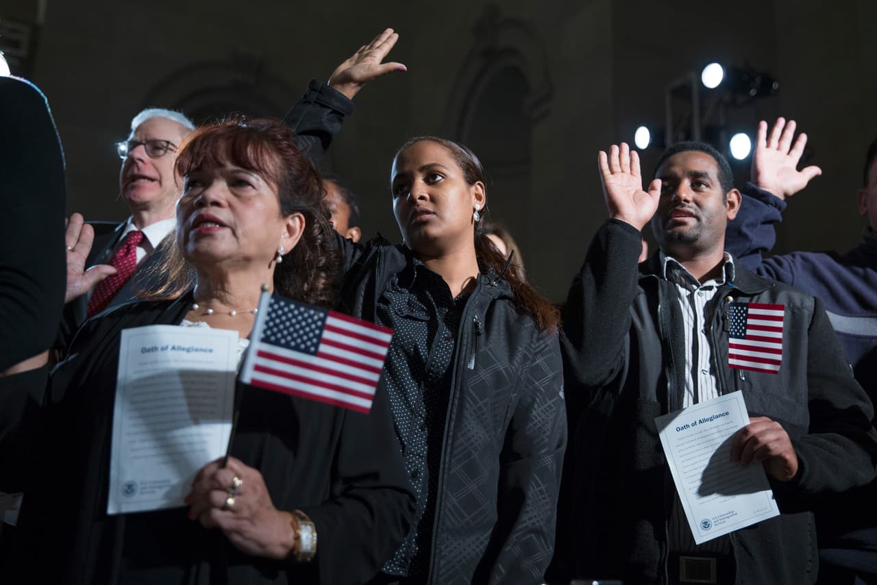 Varios participantes en una ceremonia de naturalización elevan sus manos para hacer el "Juramento de lealtad" en un evento al que asistió el presidente Barack Obama en los Archivos Nacionales en Washington, el martes 15 de diciembre de 2015. Más estadounidenses están a favor que los que se oponen al establecimiento de una forma en que los inmigrantes que viven en Estados Unidos sin permiso logren obtener la ciudadanía, según muestra un nuevo sondeo realizado por Associated Press-GfK. Aunque la mayoría de los republicanos se oponen a una medida así, no parece ser un asunto crucial para ellos a la hora de elegir a un candidato. (Foto AP/Evan Vucci)