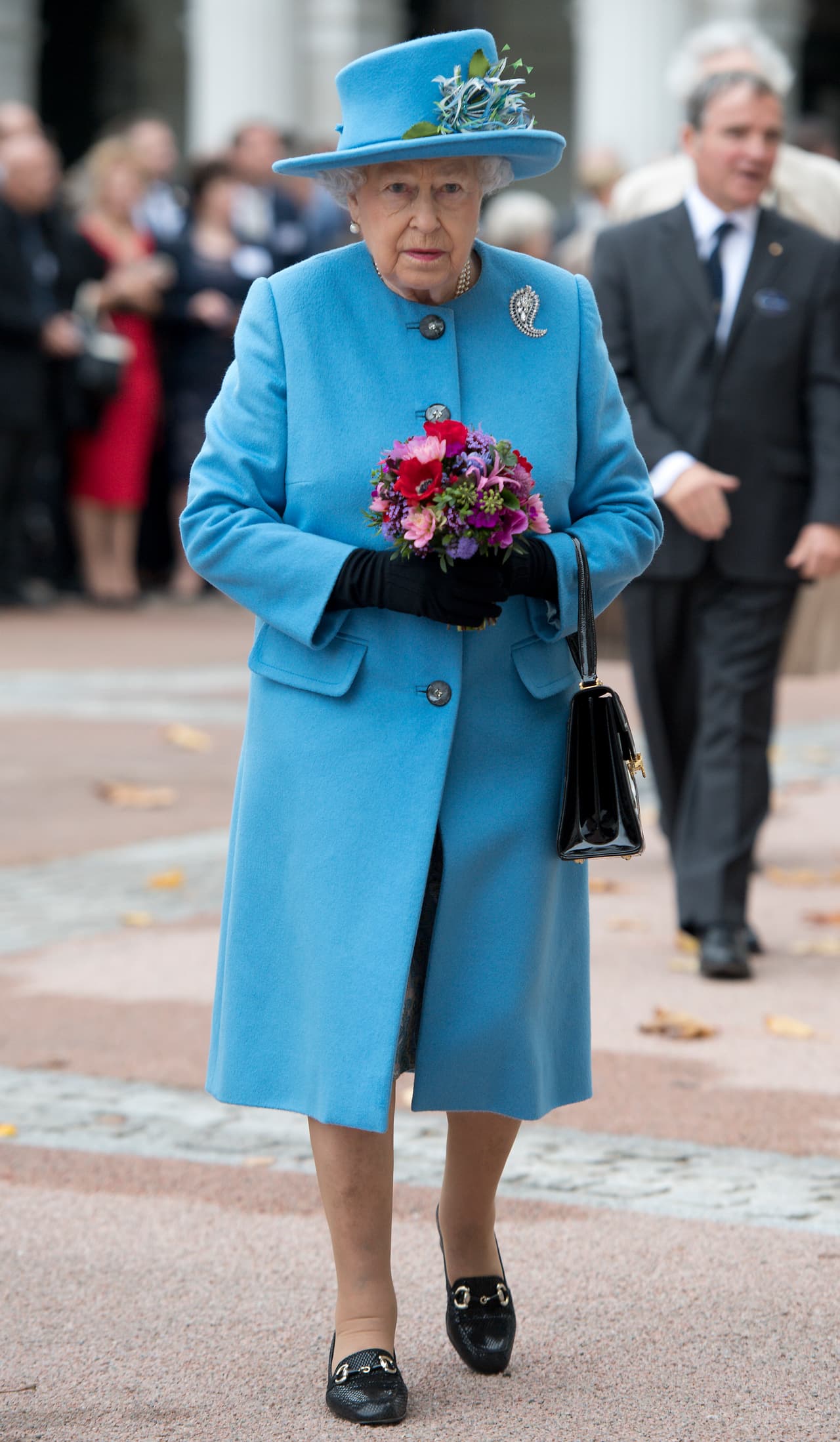 Con el elegante conjunto en azul celeste, la Reina cargó un ramo de flores que le regalaron.