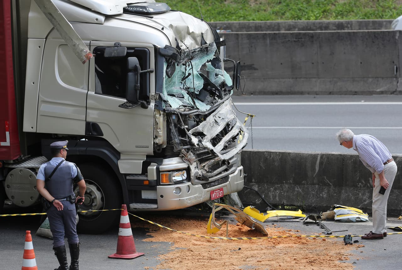 Un hombre mira los restos del helicóptero que se estrelló contra un camión de carga durante un aterrizaje de emergencia en una vía principal en Sao Paulo. El presentador de noticias de 66 años y el piloto perecieron en el accidente. La policía dice que el conductor del camión sufrió solo heridas leves.