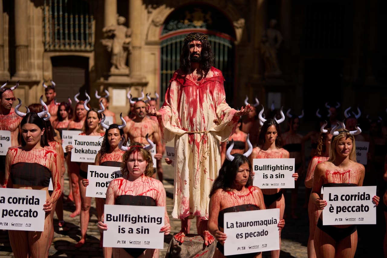 Los activistas vestidos de negro protestan en contra de la violencia que ocurre en las corridas de toros con carteles que dicen que "La tauromaquia es un pecado" en diferentes idiomas.