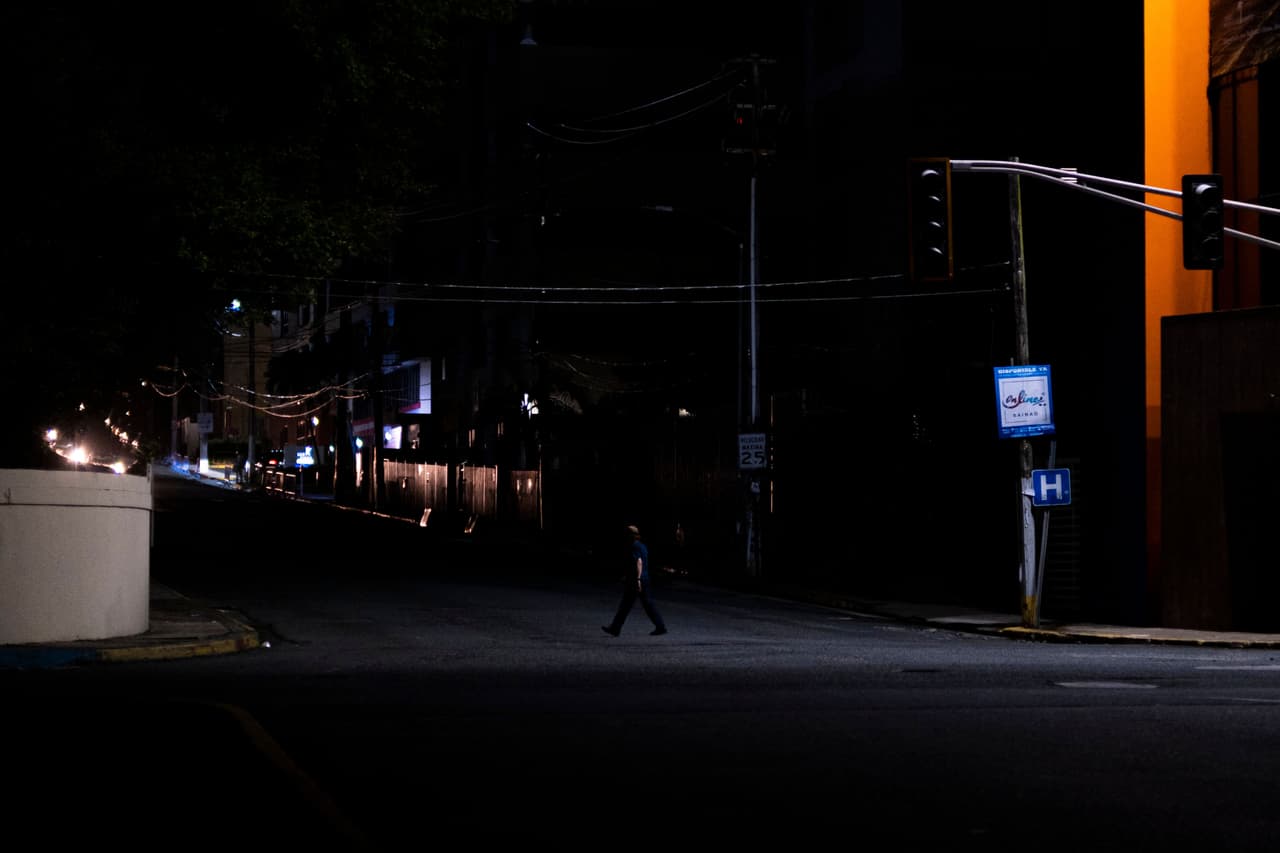 Un hombre cruza una calle que quedó a oscuras por un corte de energía en el Viejo San Juan, Puerto Rico.