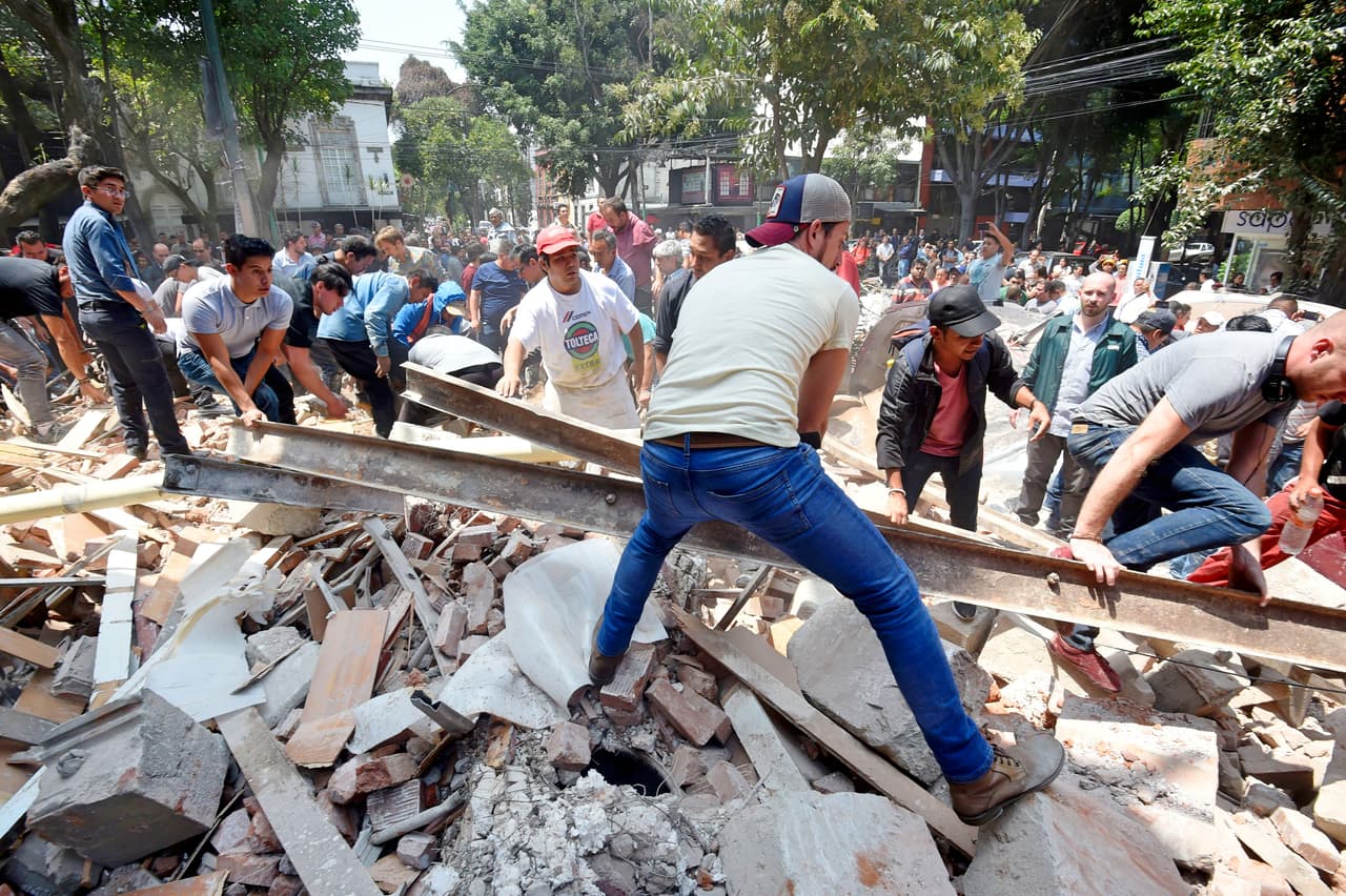People remove debris of a building which collapsed after a quake rattled Mexico City on September 19, 2017. A powerful earthquake shook Mexico City on Tuesday, causing panic among the megalopolis' 20 million inhabitants on the 32nd anniversary of a devastating 1985 quake. The US Geological Survey put the quake's magnitude at 7.1 while Mexico's Seismological Institute said it measured 6.8 on its scale. The institute said the quake's epicenter was seven kilometers west of Chiautla de Tapia, in the neighboring state of Puebla. / AFP PHOTO / Alfredo ESTRELLA (Photo credit should read ALFREDO ESTRELLA/AFP/Getty Images)
