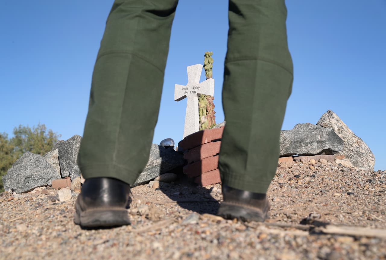 Un agente de la Patrulla Fronteriza observa la cruz de un inmigrante que perdió la vida en su intento de cruzar la frontera.