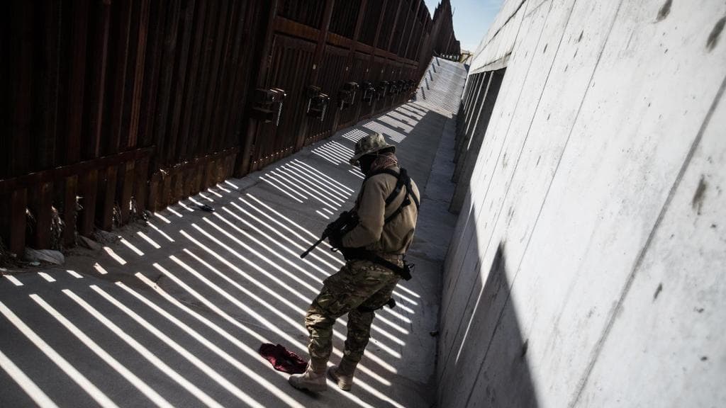 Viper, a militiamen with the United Constituonal Patriots, finds a piece of clothing in one of the walkways between the border walls at Santa Teresa, New Mexico.