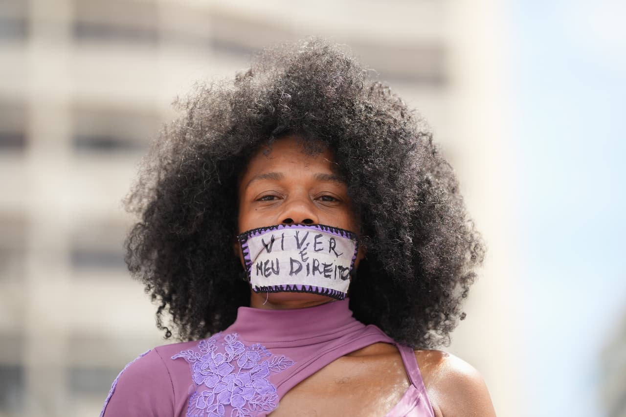 Una mujer con una cinta en la boca en la que se lee en portugués "Vivir es mi derecho" participa en una marcha con motivo del Día Internacional de la Mujer en la playa de Copacabana, en Río de Janeiro, el domingo 8 de marzo de 2026. (AP Photo/Silvia Izquierdo)