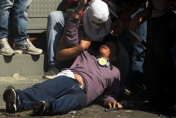 Los manifestantes auxilian a otro herido. Los estudiantes llevaron a cabo una manifestación pacífica contra el régimen del mandatario Nicolás Maduro el 12 de febrero de 2014. Motorizados uniformados y con sus caras cubiertas, dispararon contra los manifestantes, matando a dos estudiantes y a un oficial.